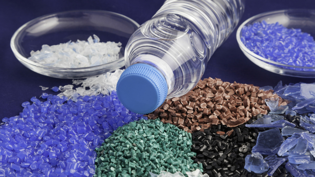 Plastic pellets and bottle fragments displayed with a clear water bottle on a surface