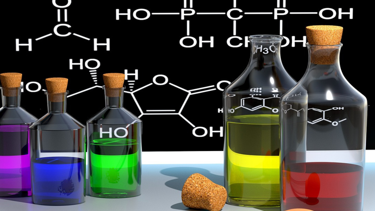 Glass bottles with colorful chemical liquids in front of molecular diagrams