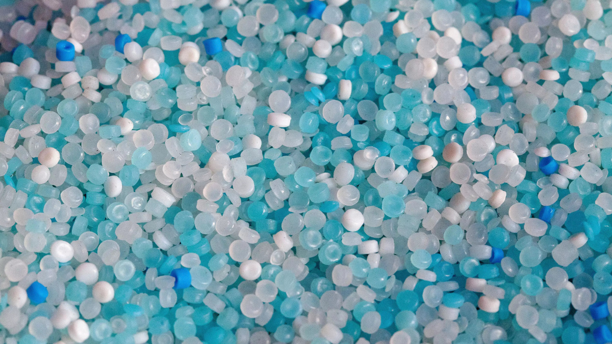 Blue and white plastic pellets used in polymer production and recycling.