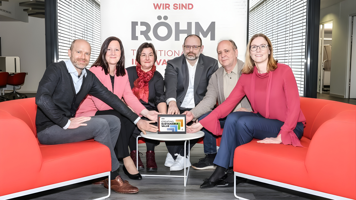 Group of Röhm and partner representatives presenting a sustainability award in an office setting