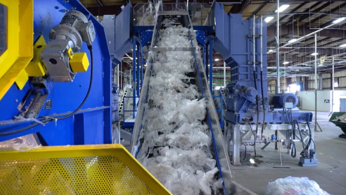 Plastic waste moving up a conveyor inside a large automated recycling facility