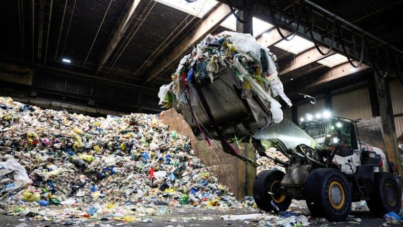 Loader lifting mixed plastic waste inside recycling facility